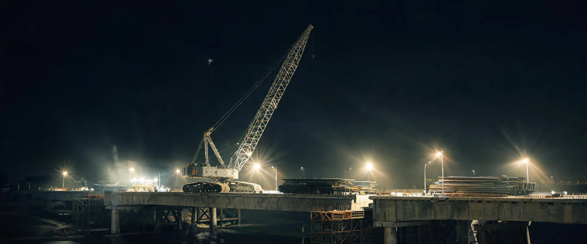 Night lift with Demag crawler crane on bridge construction site